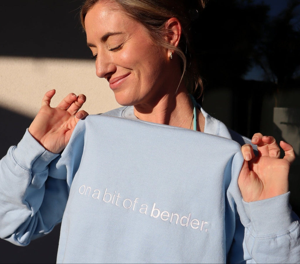 Person wearing a light blue sweatshirt with text, standing outdoors.